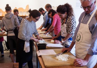 Michelle McKenzie, program director and chef at 18 Reasons, teaches an attendee to correctly chop an onion during a knife skills class at 18 Reasons Cafe in the Mission.