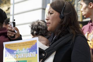 Veronica Mieto and her two-month-old Gael Isaih Comunidad stand of the steps of San Francisco City Hall during immigrant family day at on Thursday, April 28, 2016. Mieto is wearing headphones to receive translation of what speakers are saying. ( Ryan McNulty / Xpress )