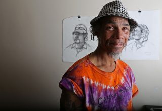 Ronnie Goodman stands in front of some portraits he drew of inmates while doing time in San Quintin State Prison. Aleah Fajardo/ Xpress