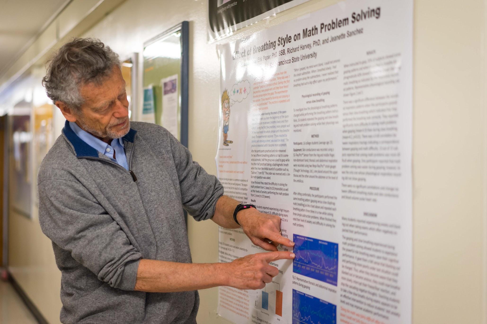 Erik Perper points to a poster on breathing techniques in the Humanities Building at SF State on Monday, April 17, 2017 (Sarahbeth Maney).