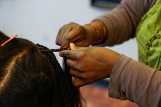 Sia Amma braids a weave into her clients hair at her salon, SF African Hair in the Tenderloin district on Wednesday, March 7. (Amarah Hernandez/ Xpress)