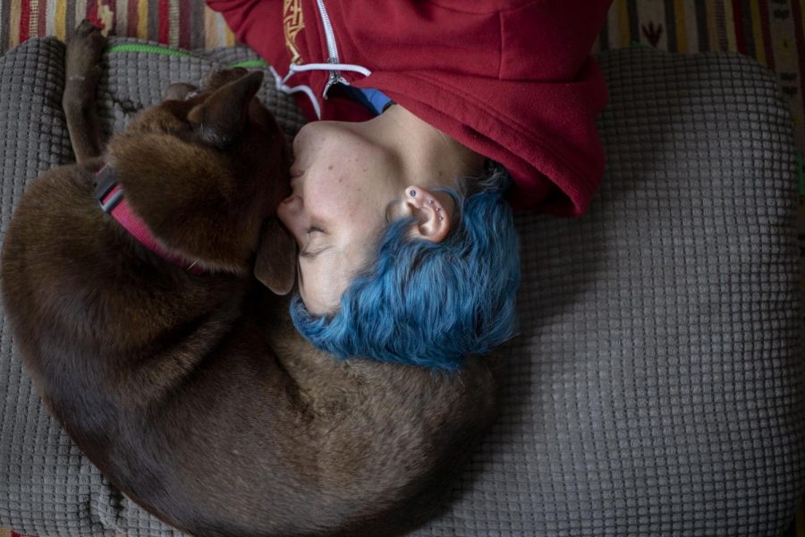 Cloud Galanes-Rosenbaum lays on her living room floor next to her service dog Billie in San Francisco, Calif. March 1, 2020. (Emily Curiel / Xpress Magazine)
