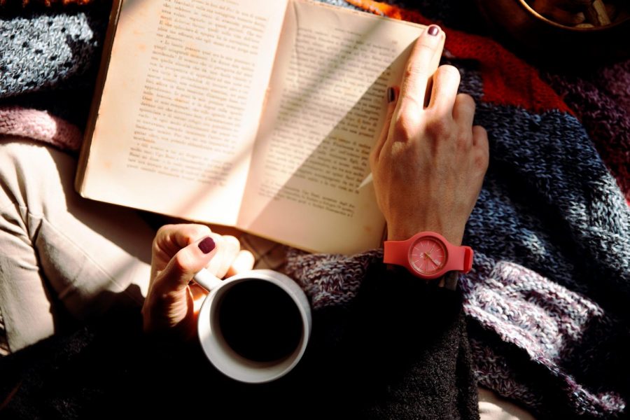 person-reading-book-and-holding-coffee-1550648