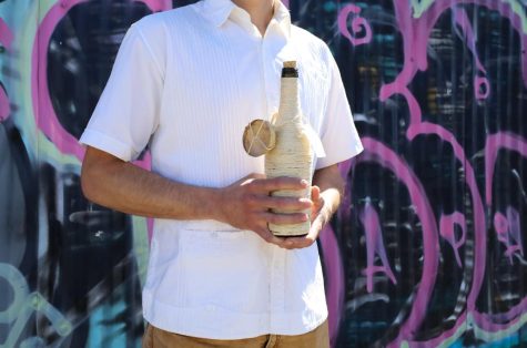 Alex Gómez Uribe, a Jalisco native, holds a bottle of mezcal from Mezcal Totoy in Oakland on March 11, 2022. The contents in the bottle were produced by Antonio Leon, a “Maestro Mezcalero” and the maguey used to make this particular mezcal was Jabali. (Bianca Heredia / Xpress Magazine)