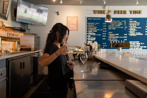 Jaime Hiraishi, a partial owner of Wine Down SF, pours a glass behind the bar at the SoMa location on May 7, 2022. Whenever possible, the owners source “natural wines” and try to support other minority-owned businesses. (Morgan Ellis / Xpress Magazine)
