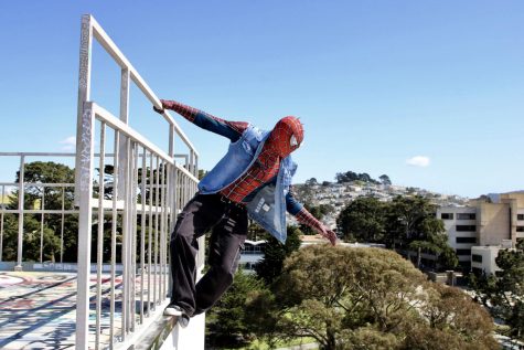 SF State Spider-Punk watches over campus as he hangs from balcony and steps atop the Cesar Chavez Student Center. (Leilani Xicotencatl / Xpress Magazine)