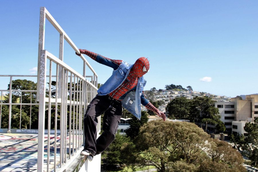 SF State Spider-Punk watches over campus as he hangs from the balcony and steps atop the Cesar Chavez Student Center. (Leilani Xicotencatl / Xpress Magazine)