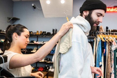 Olivia House puts a shirt against her brother Austin House’s back to check if the item fits at Wasteland on Haight Street in San Francisco, Calif., on March 26, 2023. (David Jones / Xpress Magazine)