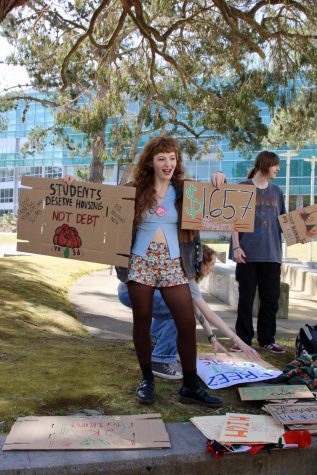 Young Democratic Socialists of America member Bethany Padilla holds a sign for a student housing protest at SF States Malcom X Plaza. (Leilani Xicotencatl / Golden Gate Xpress)