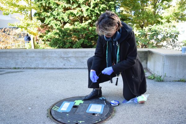  SUPER project lead Ben Mingoa deploys a new tampon to the manhole outside Village in Centennial Square. The tampon absorbs wastewater, which is used by the Anand lab for microbial research. 