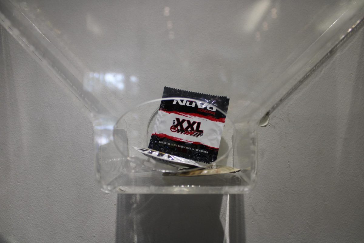Three condoms are seen in a condom dispenser in the Cesar Chavez Student Center. 