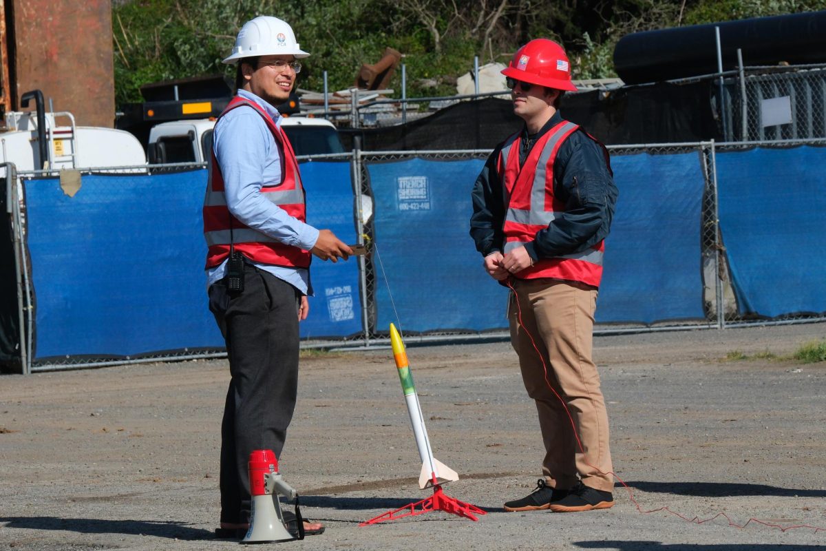Oskar Kenyatta Garcia (left) and Marc McClure (right) prepare the rocket during a Fog City rocket launch in Lot 25 on campus