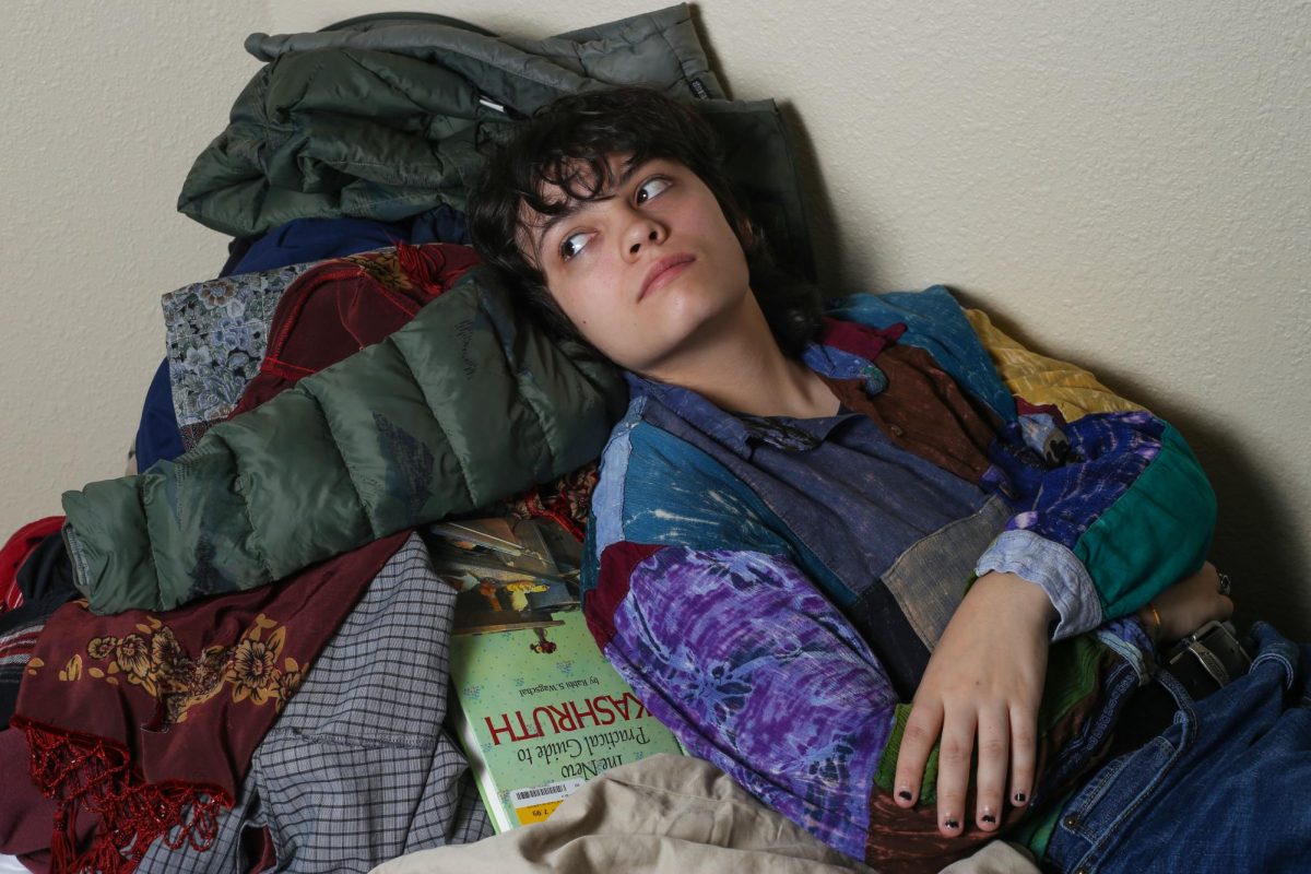 Cordy Walker lays on his bed where he keeps piles of clothes, as a result of both his inattentive and hyperactive ADHD.