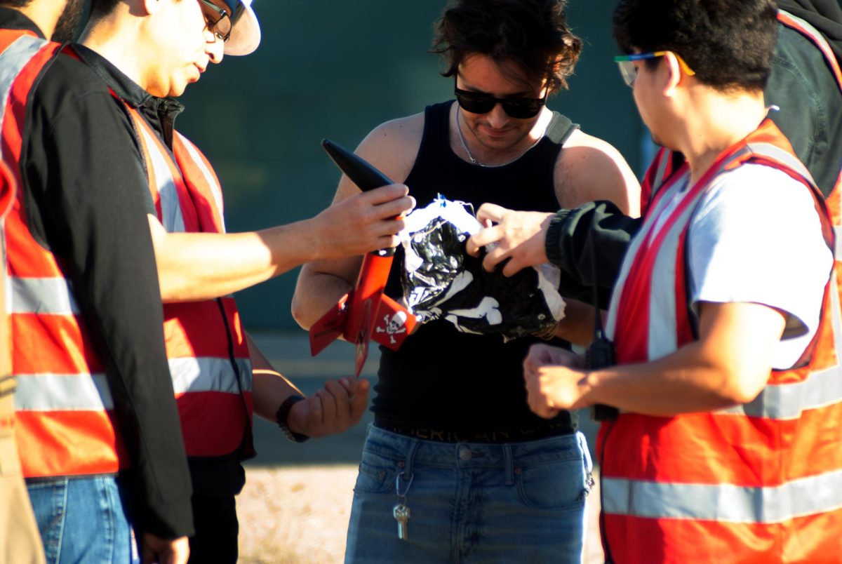 From left: Anthony Gamarra, Marc McClure, and Jorge Aguilar assess a workhorse rocket post-landing in Lot 25 at SF State. (Rodliam Suspene / Xpress Magazine)