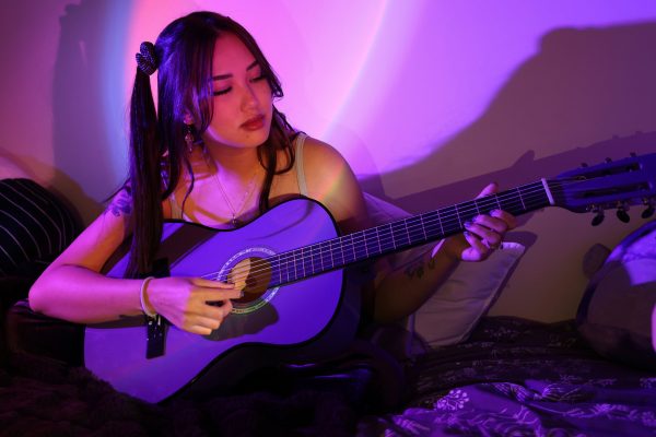 Amber Brown plays her guitar in her dorm room. Brown’s original song, using the tune of “What Was I Made For” by Billie Eilish, gained 1.1 million views on TikTok. (Braelyn Furse / Xpress Magazine)