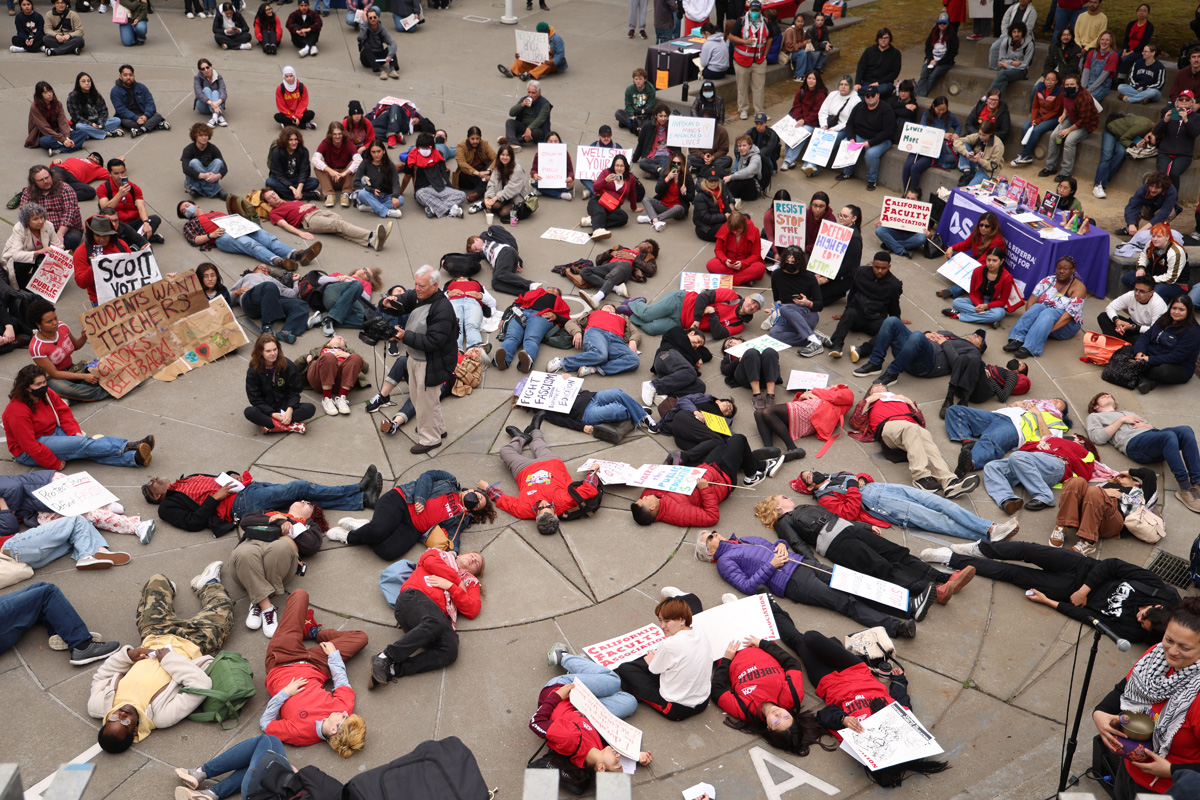 Protesters perform a “die-in” for CSU budget cuts in Malcolm X Plaza during the National Day of Action for Higher Ed. (Braelyn Furse / Golden Gate Xpress)