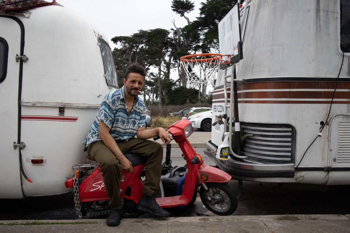 Mohamed Ali shows off his scooter, a red 1986 Honda Spree, that sits outside his RV in Daly City, on Sept. 25, 2025. (Jolie Willson / Xpress Magazine)
