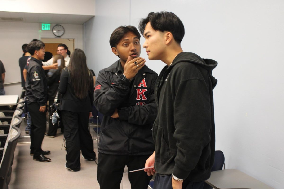 AKPsi fraternity member, Luke Htet, talks to potential new member at the  informational night on Sep. 8th, 2025. (Photo by Lara Magdesian / Xpress )