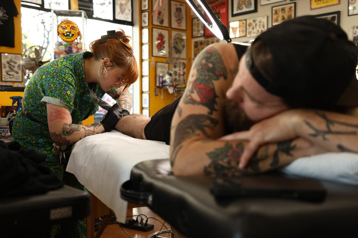 Ethan Indorf lays down as Zoe Weitala begins the lining process. He chose a goat from Weitala’s flash sale. Inspired by a real-world goat, he names it “Riley.”. (Vanden Harris / Xpress Magazine)