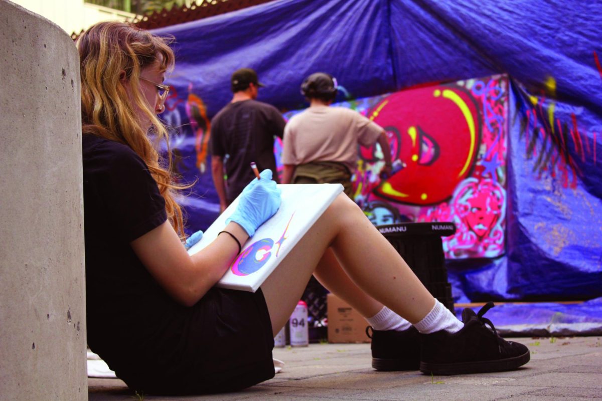 In the mural and graffiti class, Ursula Sterkel draws while her classmates practice their graffiti skills. (Isabella Balzarano / Xpress Magazine)